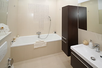 Modern beige bathroom with bathtub and dark wood vanity