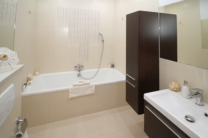 Modern beige bathroom with bathtub and dark wood vanity