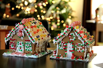 Two decorated gingerbread houses with Christmas tree background