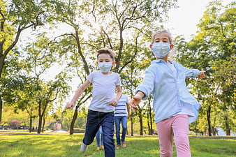 Children running in park wearing face masks