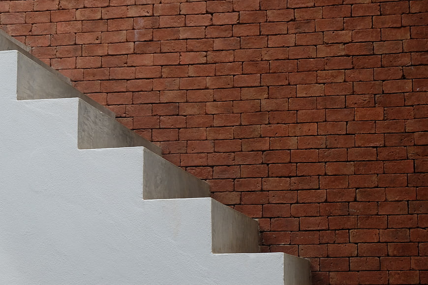 White Concrete Staircase Against Red Brick Wall