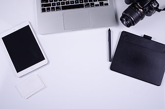 Minimalist flat lay of creative workspace with laptop, camera, and tablet