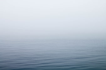 Minimalist foggy ocean horizon with calm water ripples