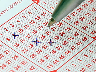 Close-up of a lottery ticket with numbers crossed out by a pen