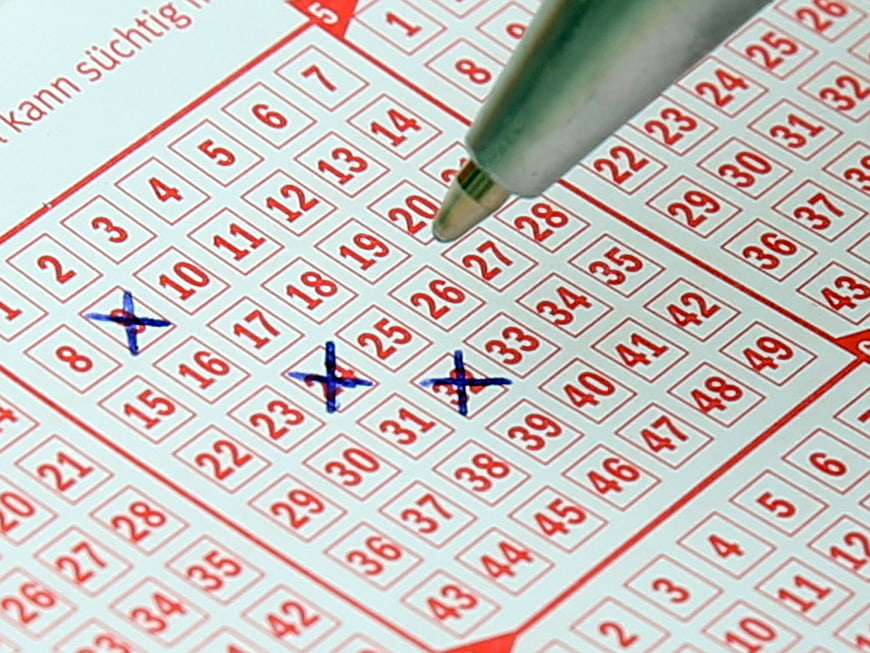 Close-up of a lottery ticket with numbers crossed out by a pen