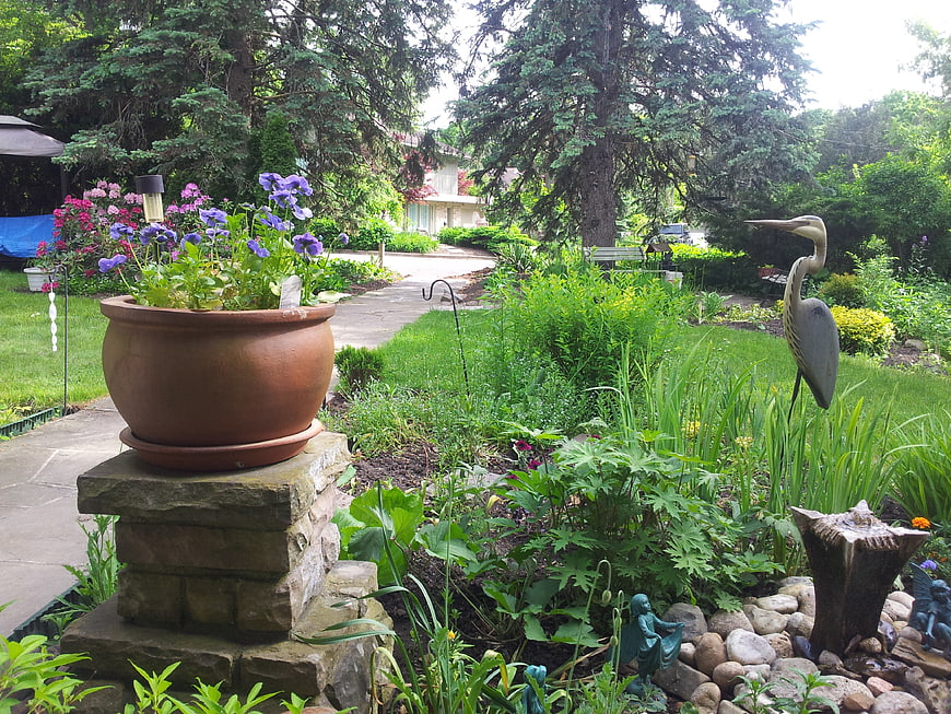 Lush Garden Pathway with Terracotta Pot and Bird Sculpture