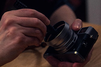 Close-up of hands cleaning vintage camera lens