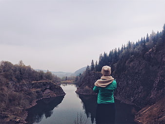 Woman in Green Jacket Looking at River Valley Landscape