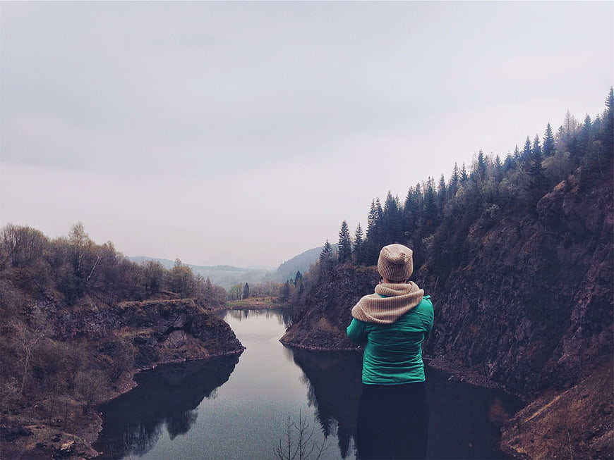 Woman in Green Jacket Looking at River Valley Landscape