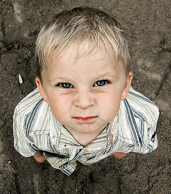 High angle portrait of young boy looking up from sand