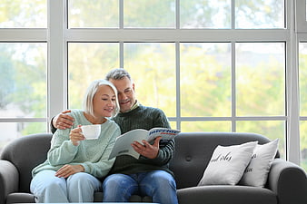 Happy Senior Couple Reading Magazine on Sofa