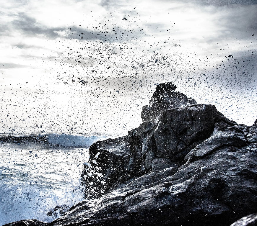 Dramatic Ocean Waves Crashing Against Dark Rocky Cliff