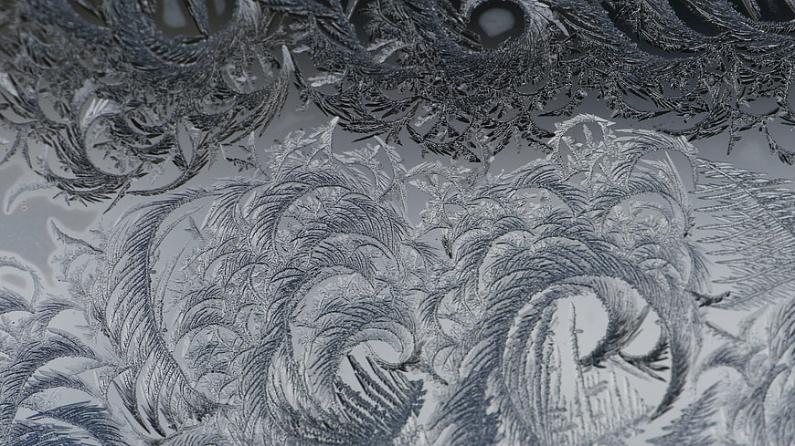 Intricate frost patterns on frozen glass window