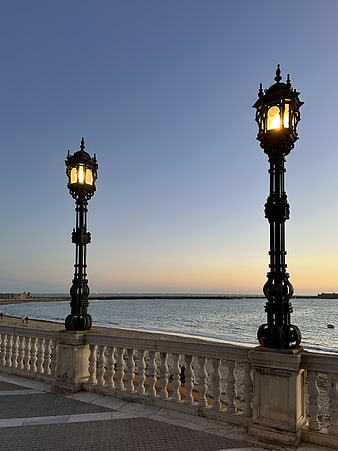 Ornate vintage street lamps on seaside promenade at dusk