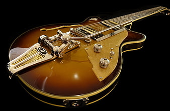 Close-up of vintage electric guitar with gold hardware on black background