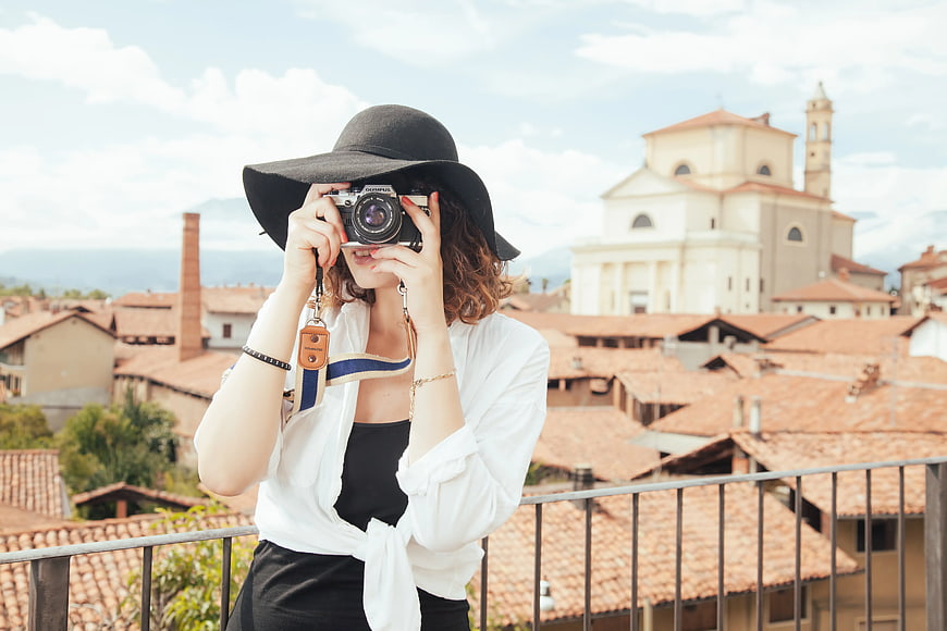 Woman with Camera on Balcony Overlooking European Cityscape