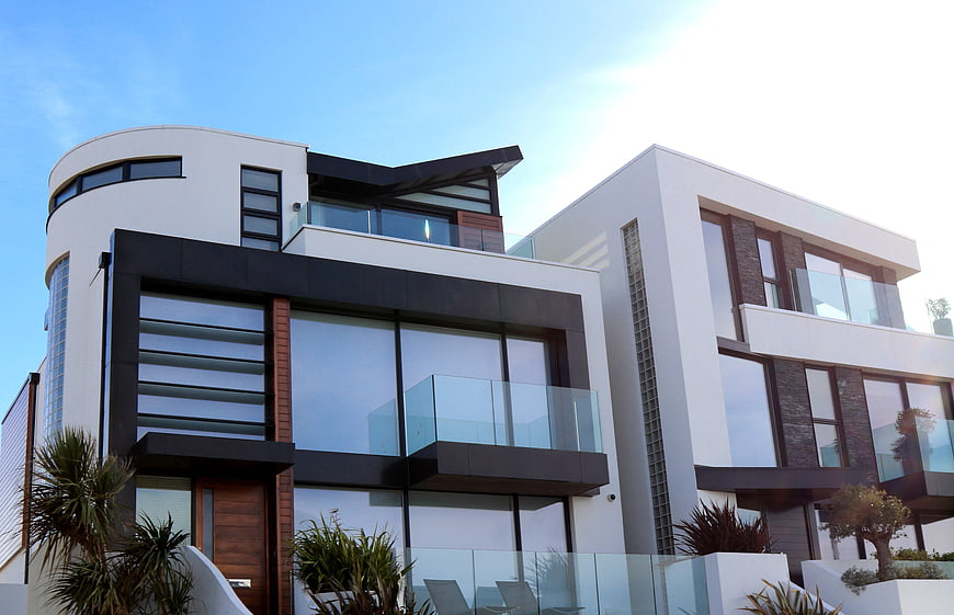 Modern luxury white house with glass balconies and blue sky