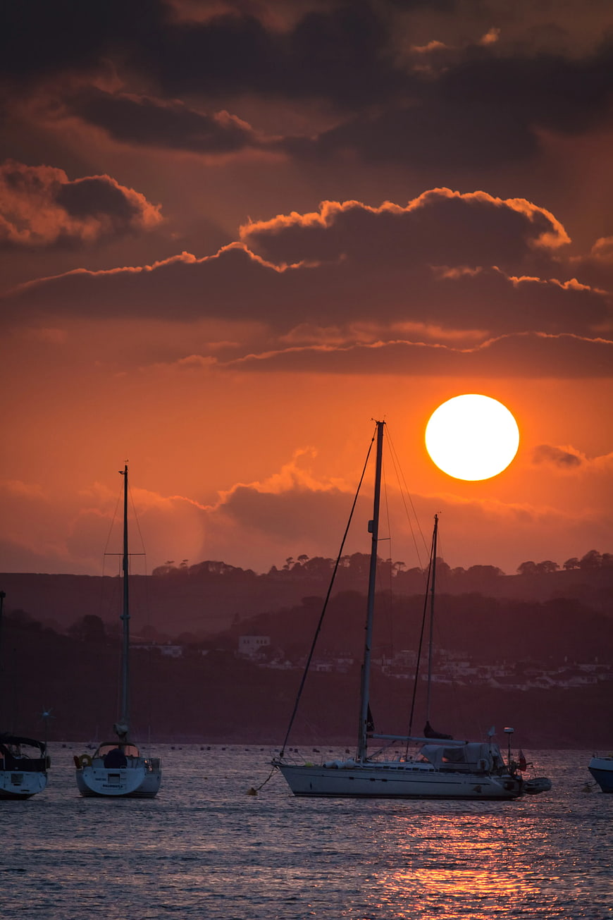 Sailboats Silhouetted Against Dramatic Orange Sunset Sky