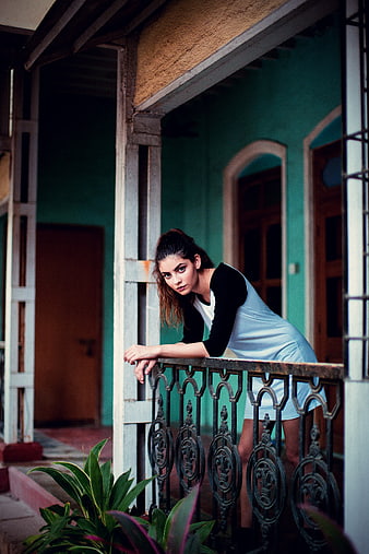 Young woman leaning on balcony railing in teal house