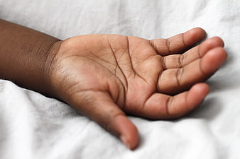 Close-up of a child's open hand on white fabric