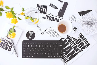 Top view creative workspace with keyboard, coffee, and typography