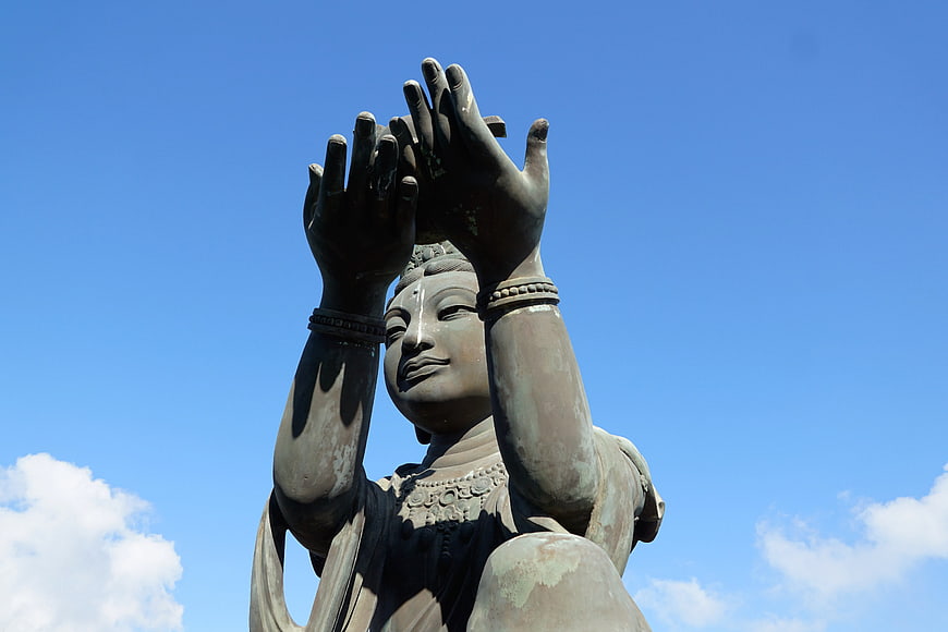 Low angle view of bronze Guanyin statue against blue sky