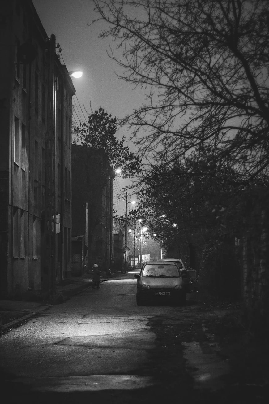 Moody black and white night street scene with parked car