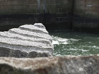 Textured granite rock near flowing water and stone wall