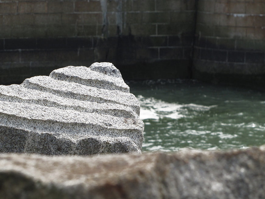 Textured granite rock near flowing water and stone wall