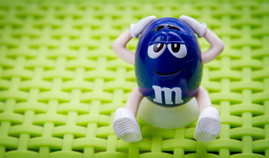Blue M&M Character Toy Sitting On Green Woven Surface