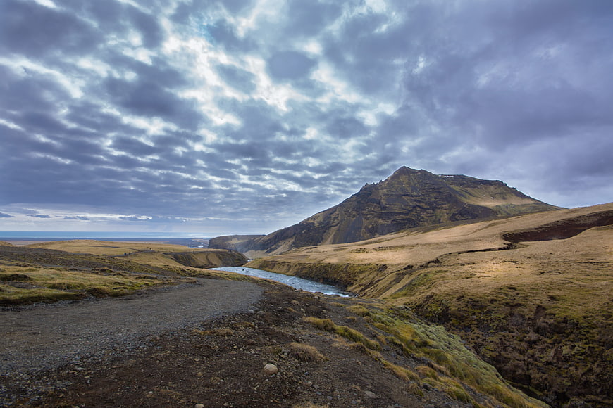 Dramatic Icelandic Landscape With River, Mountain, And Overcast Sky