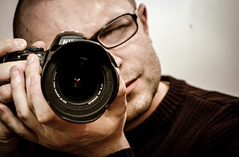 Close-up of male photographer holding DSLR camera lens