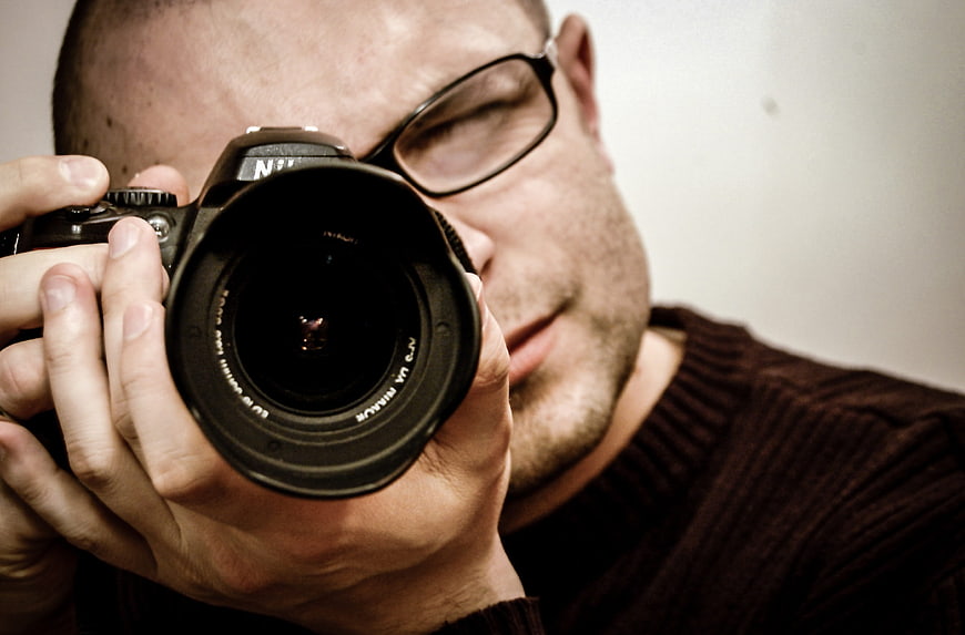 Close-up of male photographer holding DSLR camera lens