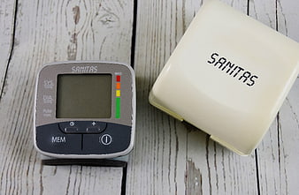 Digital Blood Pressure Monitor on White Wooden Background