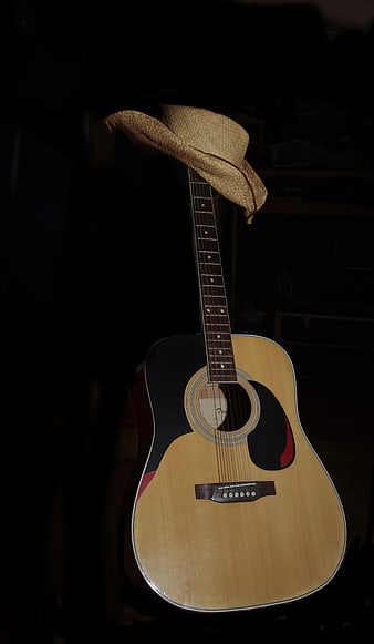 Acoustic Guitar with Straw Hat in Dark Room