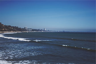 Wide coastal view of ocean waves and city skyline