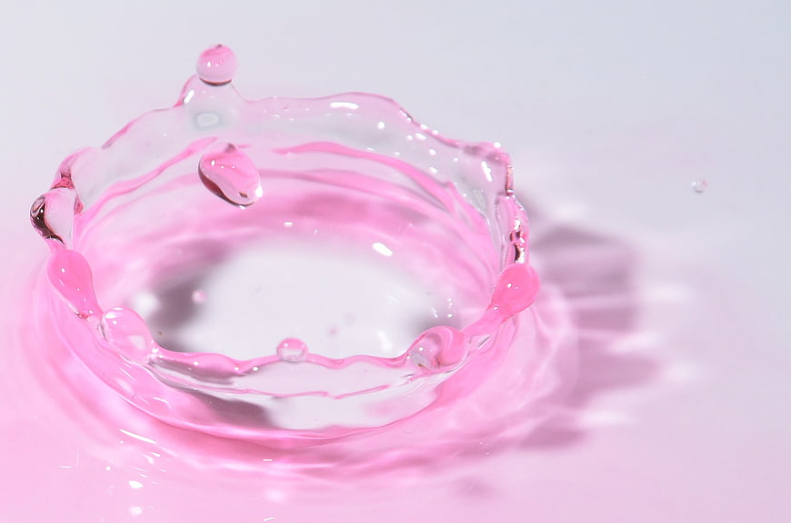 Pink liquid splash crown on white background