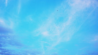 Airplane flying high in blue sky with wispy clouds