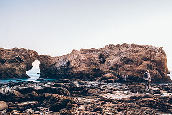 Photographers capturing coastal rock arch formation