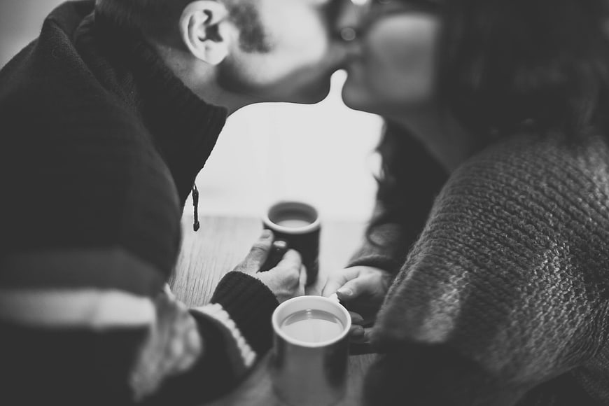 Intimate Black and White Photo of Couple Kissing Over Coffee