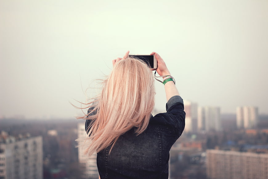 Woman Taking Photo of City Skyline with Smartphone
