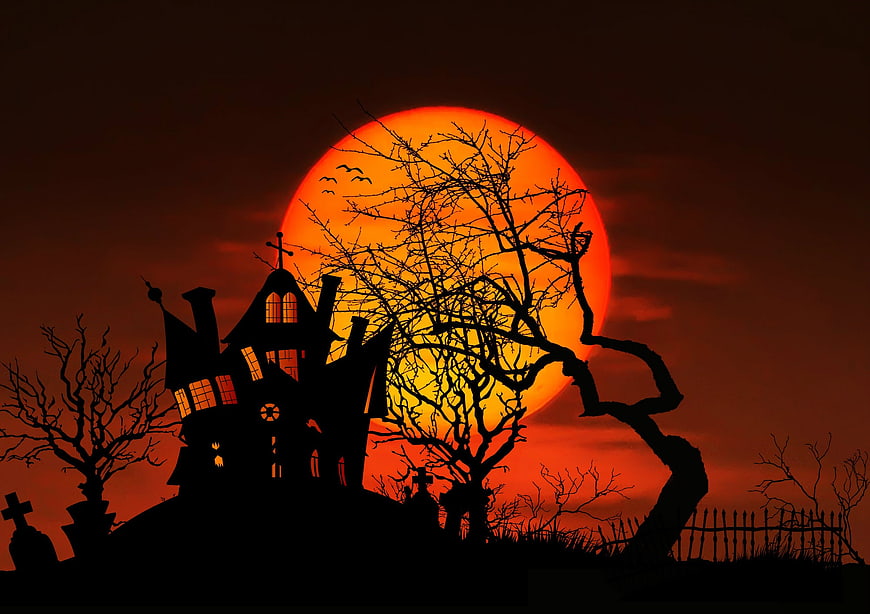 Spooky haunted house silhouette against giant orange moon