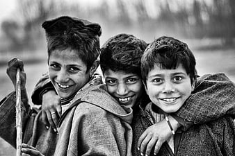 Three smiling boys hugging in black and white portrait