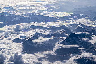 Aerial View of Snow-Capped Mountain Peaks Above Clouds