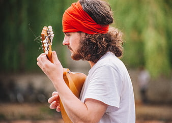 Man with Red Headband Tuning Acoustic Guitar Outdoors