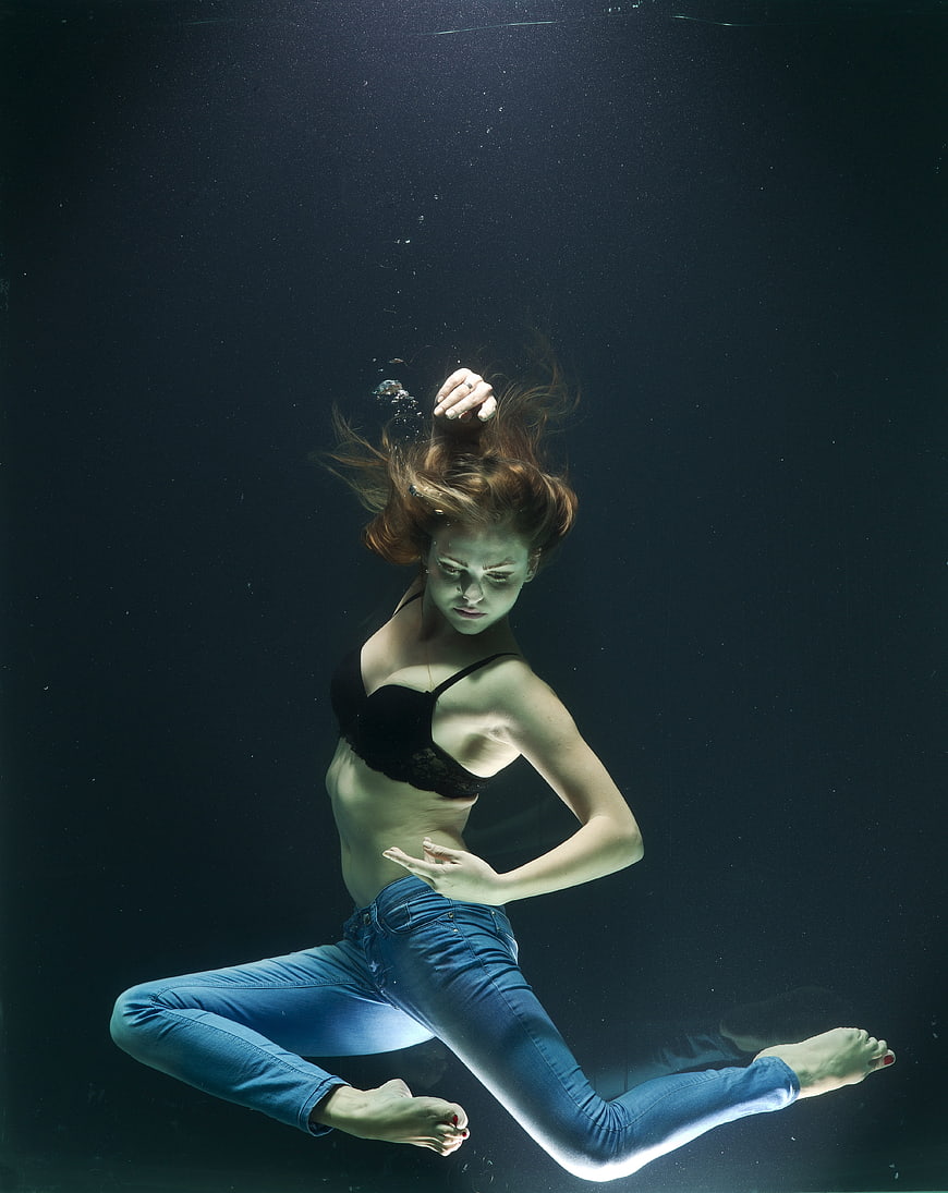 Underwater fashion portrait of a woman in blue jeans and black bra