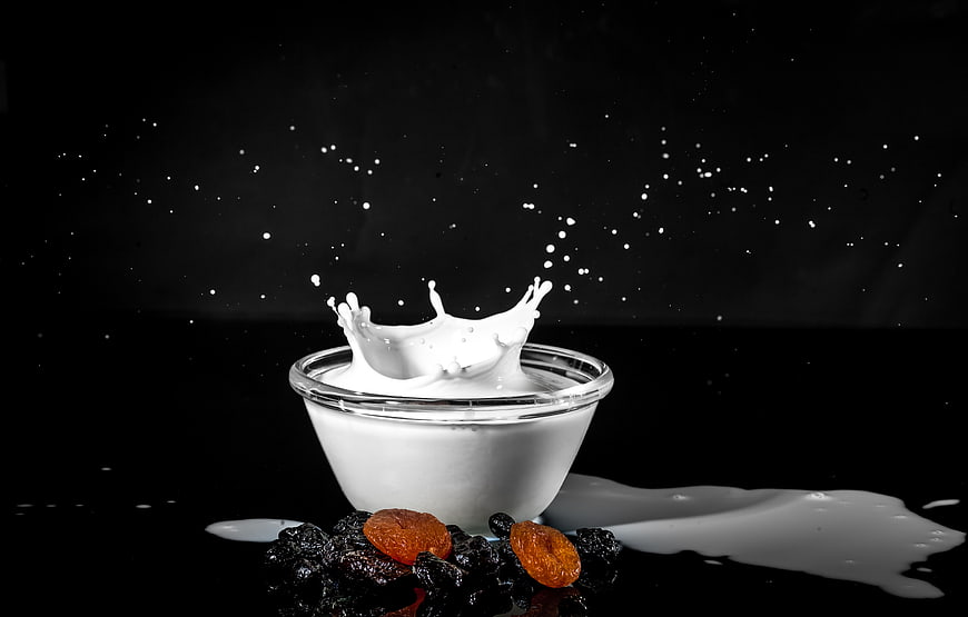 Yogurt Splash with Raisins and Apricots on Black Background