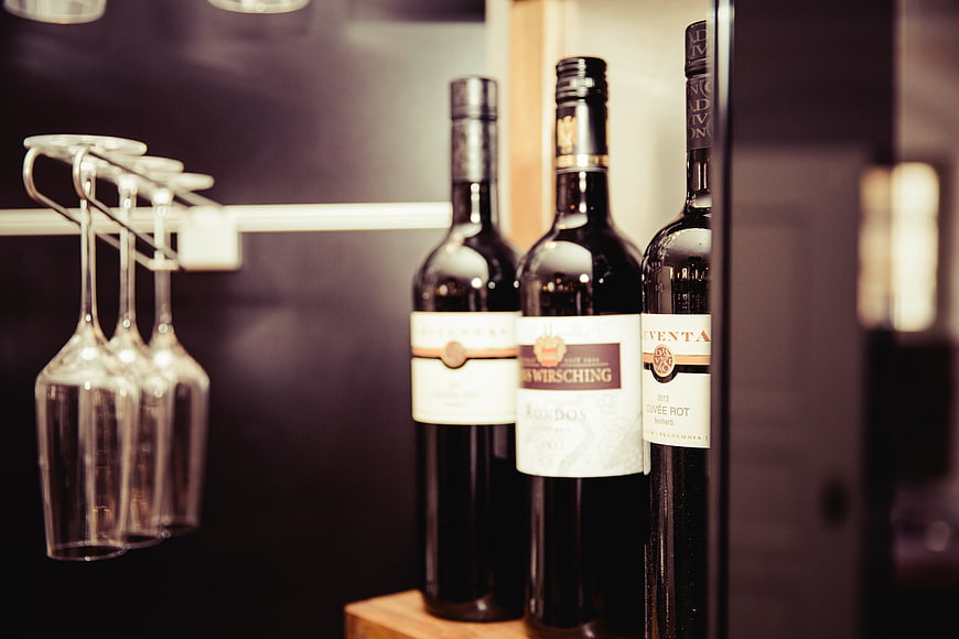 Wine bottles and glasses on a shelf in a bar
