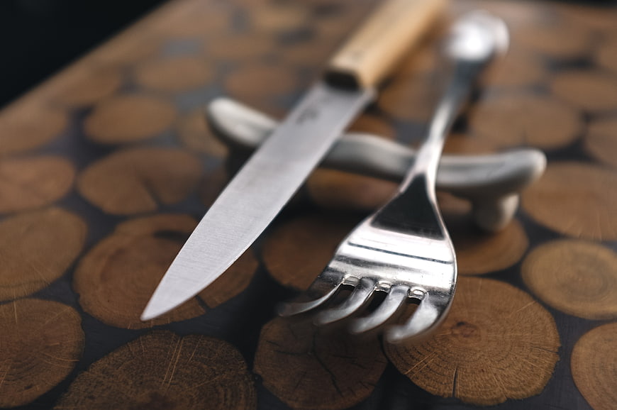 Close-up of silver fork and steak knife on wooden board
