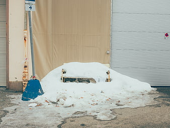 Snow-covered bench in urban alleyway with melting ice